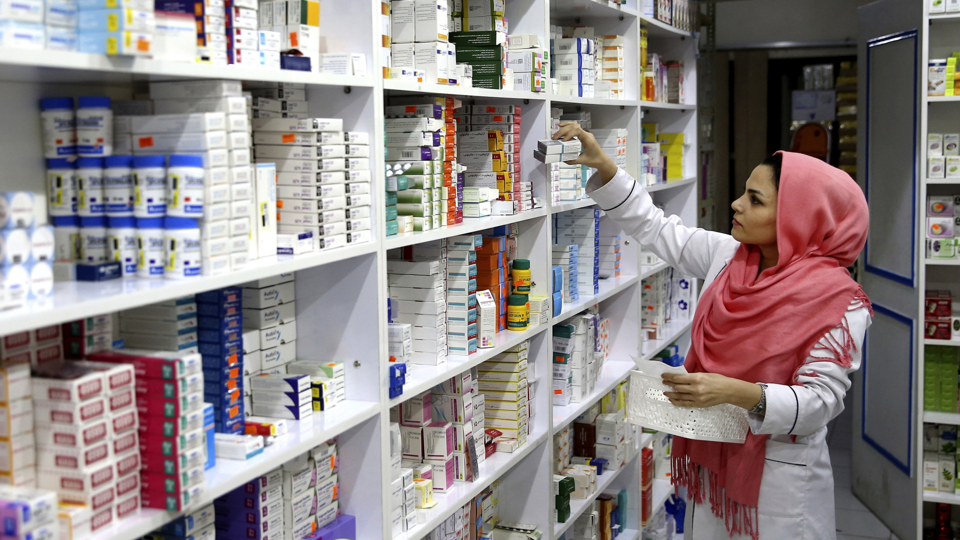 Eine Mitarbeiterin nimmt in Teheran Arzneipackungen aus einem Apothekenregal. (November 2018) | dpa