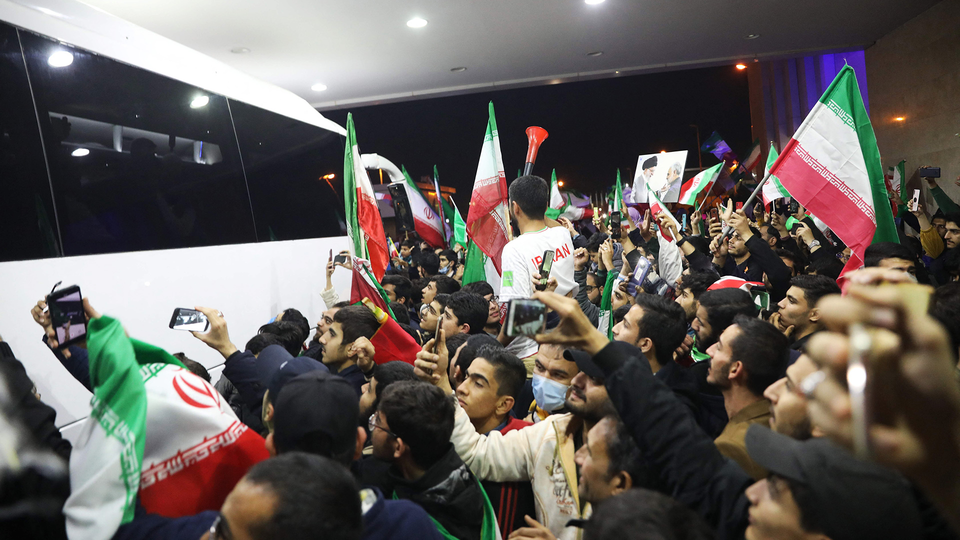 Iranische Fußballballfans umringen einen Mannschaftsbus. | AFP