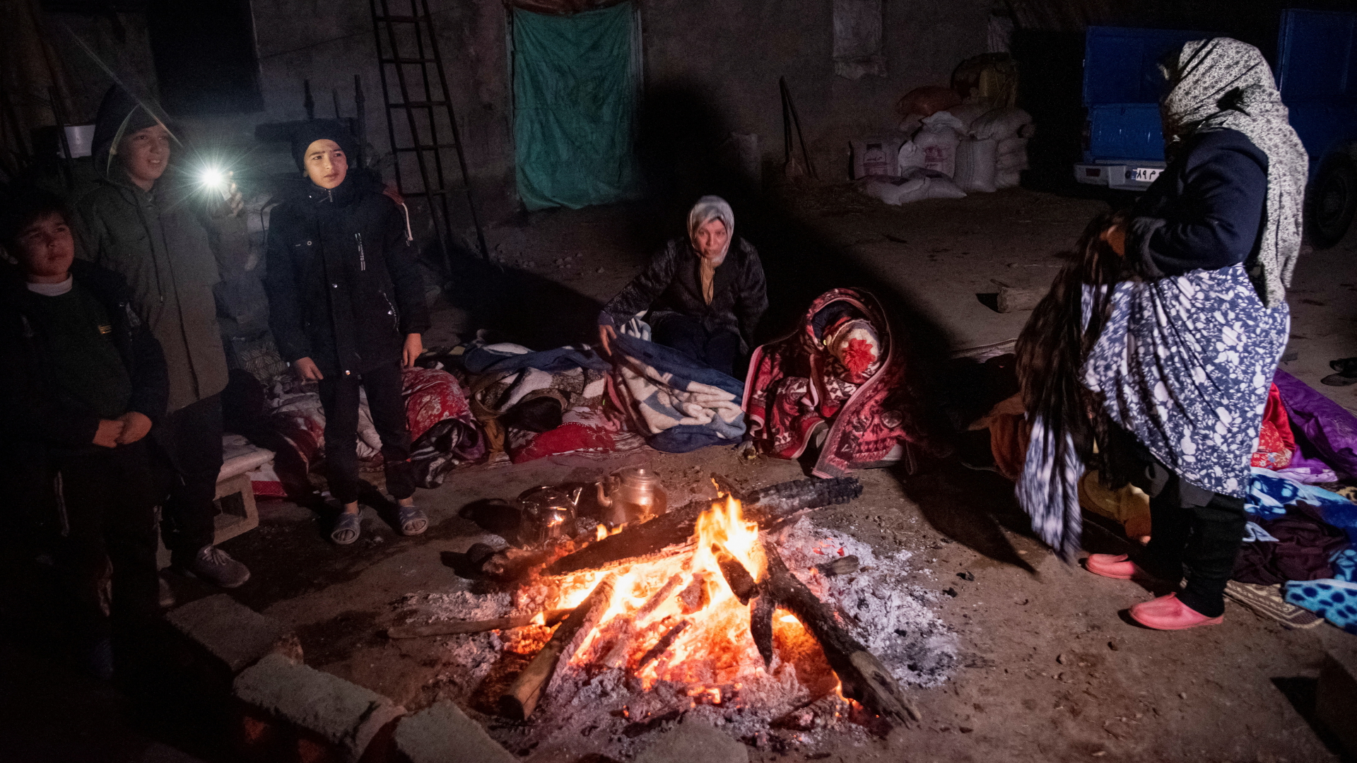 Zwei Frauen und drei Kinder stehen in der Region um die iranische Stadt Khoy nach einem Erdbeben rund um ein Lagerfeuer. | via REUTERS