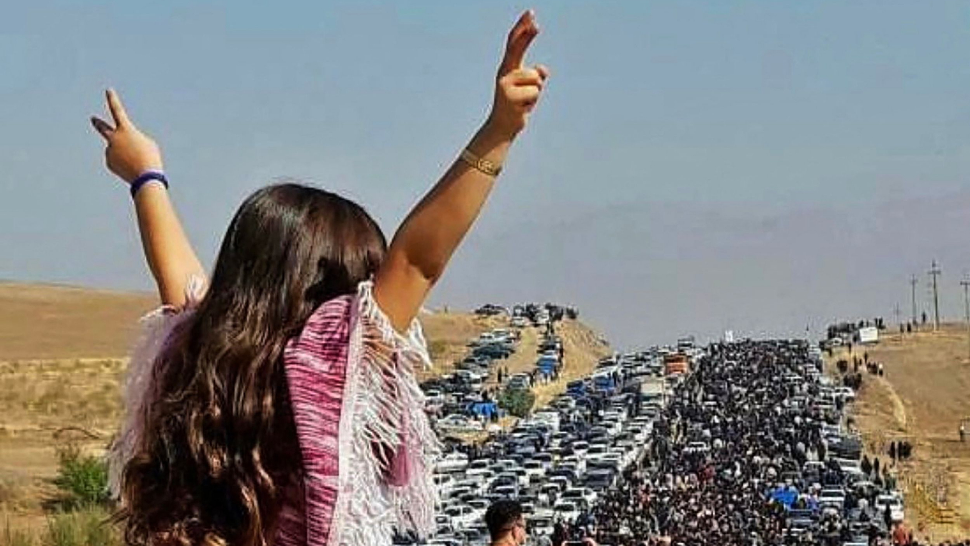Das Foto zeigt  eine Frau, die ohne Kopftuch auf einem Auto steht - vor ihr viele Menschen auf der Straße. In sozialen Netzwerken kursieren Aufnahmen, die Zehntausende auf dem Weg zu Mahsa Aminis Grab in Saghes zeigen sollen. | AFP