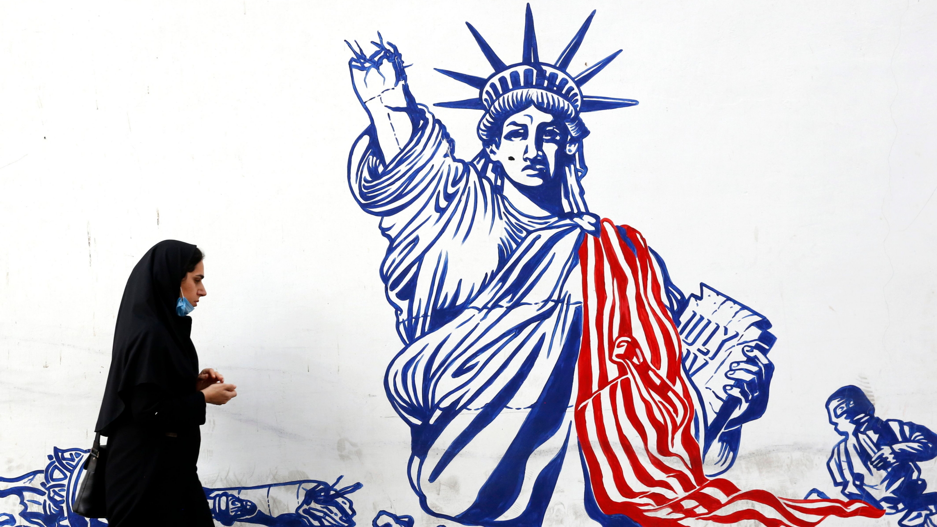 Eine Frau geht in Teheran an einem Wandbild vorbei, dass die verstümmelte Freiheitsstatue zeigt. | ABEDIN TAHERKENAREH/EPA-EFE/Shut