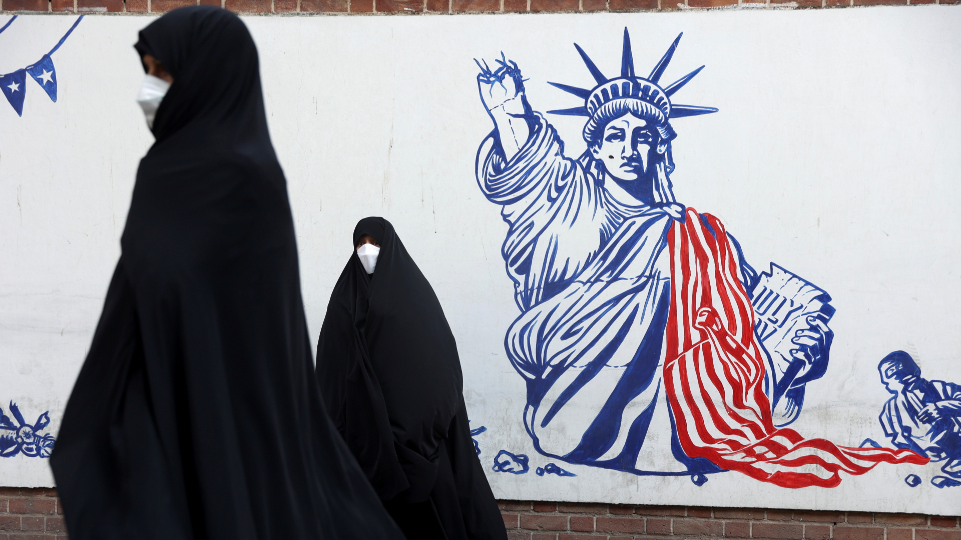 Eine verschleierte Frau geht im Iran an einem Anti-USA-Wandgemälde vorbei (Archivbild). | via REUTERS