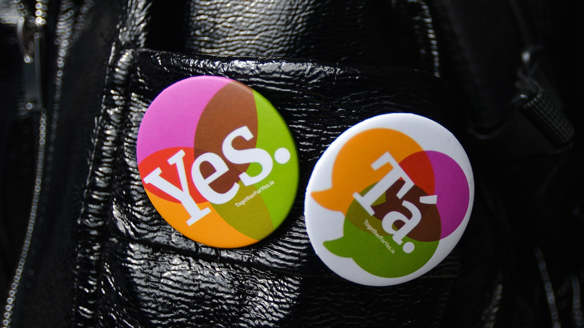 "Ja" in englischer und irisch-gälischer Sprache steht auf zwei Ansteckern an einer Lederjacke. | picture alliance / NurPhoto