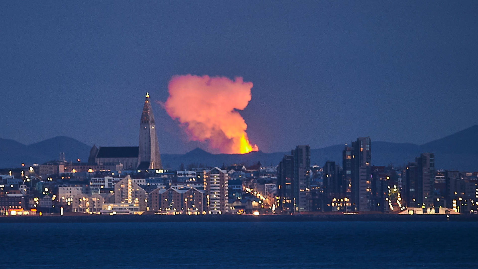 Hinter Reykjavik ist der Feuerschein von Lava zu sehen, die aus dem Vulkan Fagradalsfjall austritt. | AFP