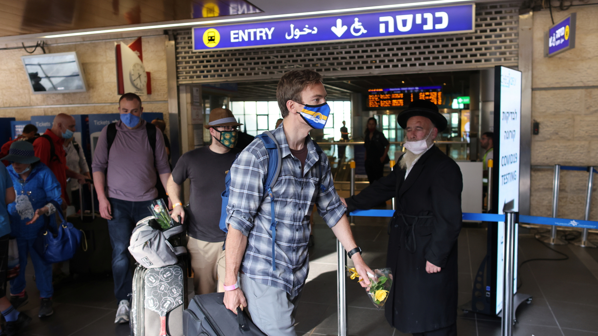 Touristen mit Corona-Masken verlassen den Flughafen Ben Gurion in Tel Aviv mit Gepäck. | REUTERS