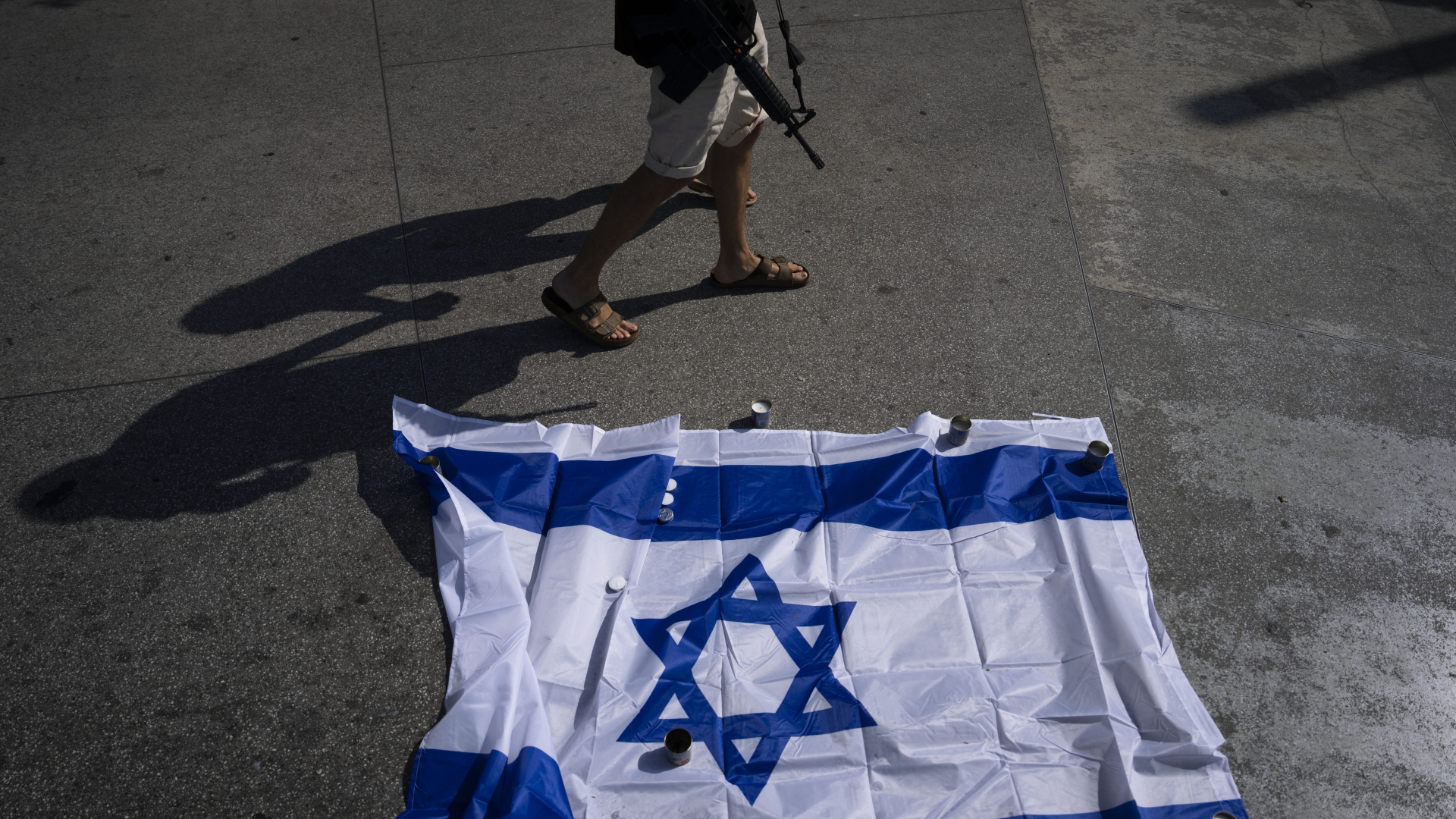 Ein israelischer Soldat, der nicht im Dienst ist, geht an Kerzen und der Nationalflagge Israels vorbei.