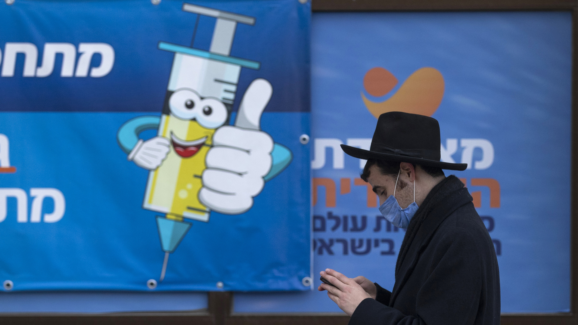 Ein Mann geht in Israel an einem Werbeplakat für Impfungen vorbei. | picture alliance/dpa/AP
