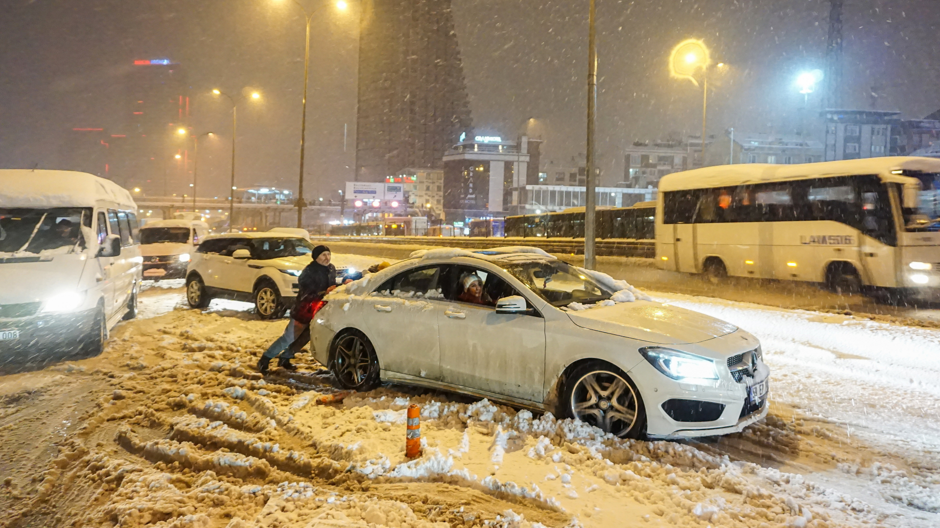 Ein Mann schiebt ein Auto auf einer schneebedeckten Straße in Istanbul. | dpa