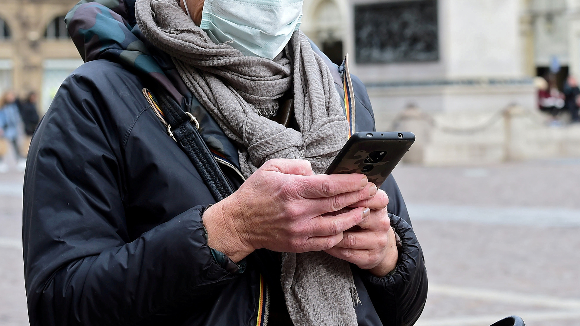Eine Frau mit Handy und Schutzmaske in Turin, Italien | REUTERS
