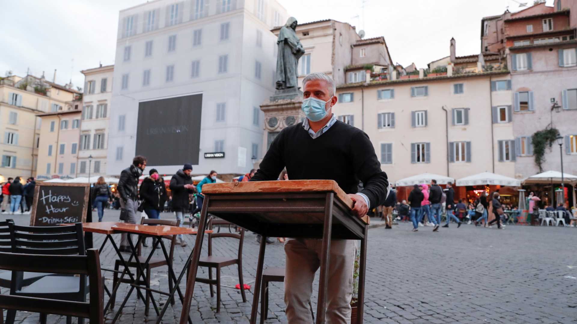 Kurz vor dem Lockdown räumt ein Mann vor einem Restaurant in Rom die Tische weg. | REUTERS