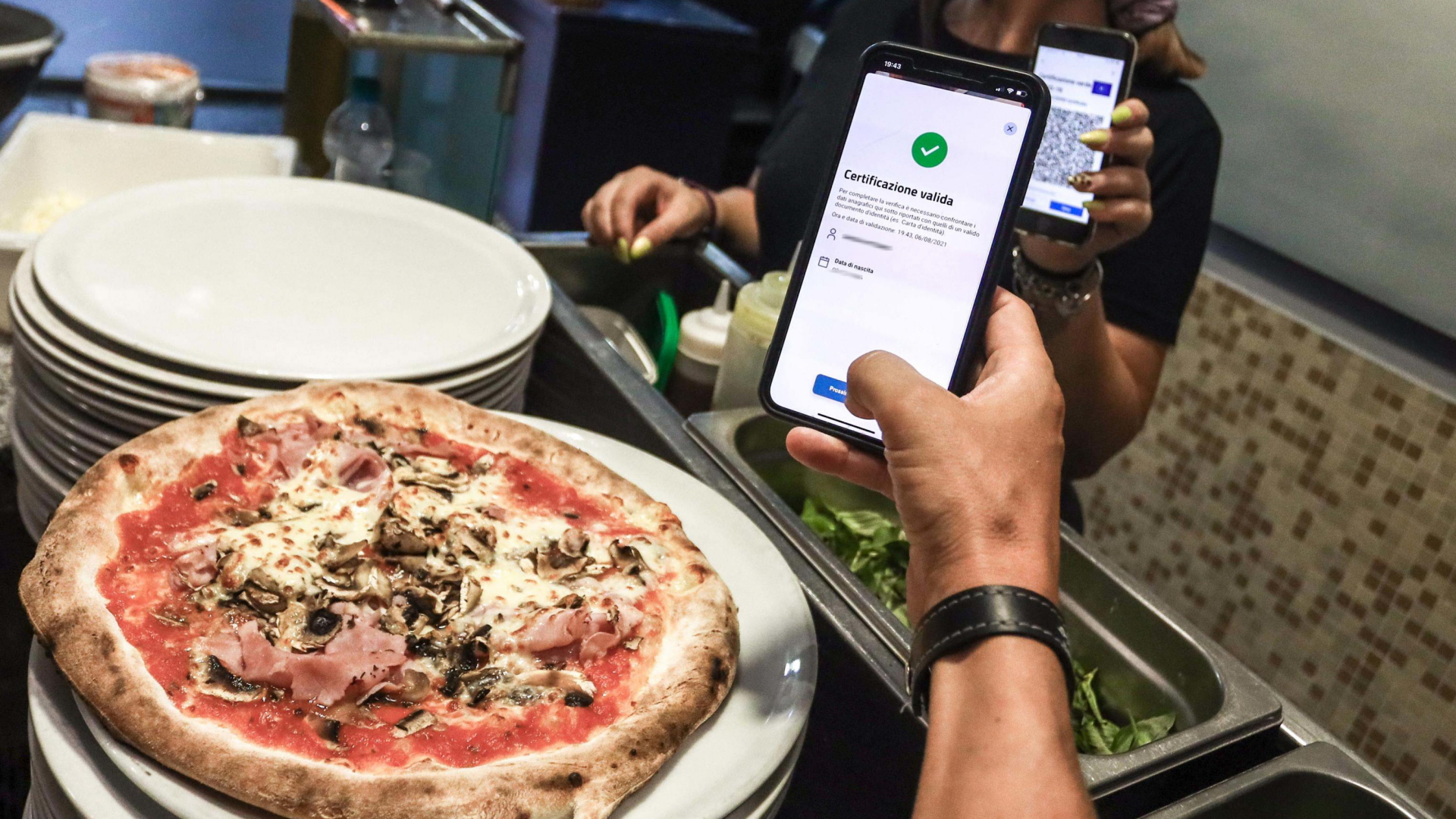 In einer Pizzeria in Turin wird der Greenpass einer Besucherin geprüft. | EPA