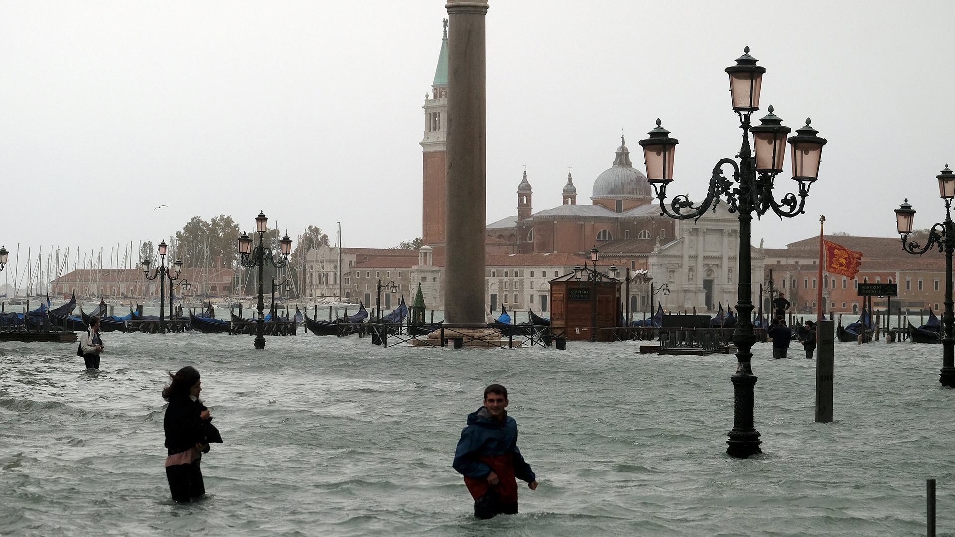 Menschen stehen im Wasser auf dem überschwemmten Markusplatz in Venedig. | Bildquelle: REUTERS