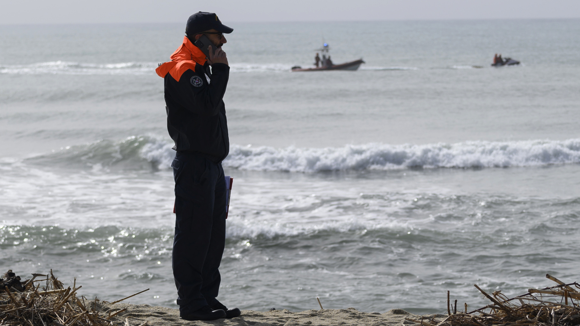 Ein Offizier der italienischen Küstenwache telefoniert an einem Strand (Archivbild). | dpa