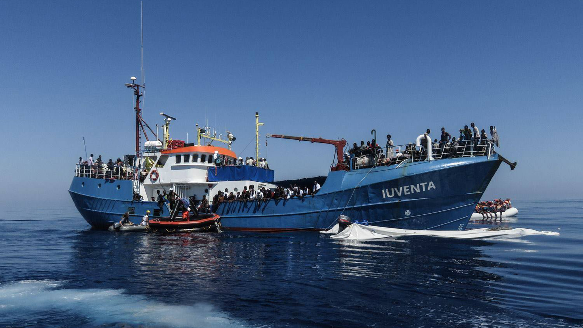 Flüchtlinge sitzen bei einem Einsatz an Bord des Schiffes «Iuventa» im Mittelmeer (Archivbild vom 15.09.2017). | picture alliance / -/IUVENTA Jug