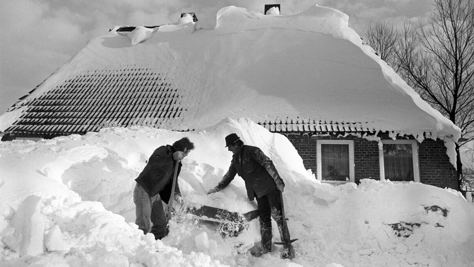 Zwei Anwohner im schleswig-holsteinischen Loose versuchen ein Auto von dem meterhohen Schnee zu befreien. | Bildquelle: dpa