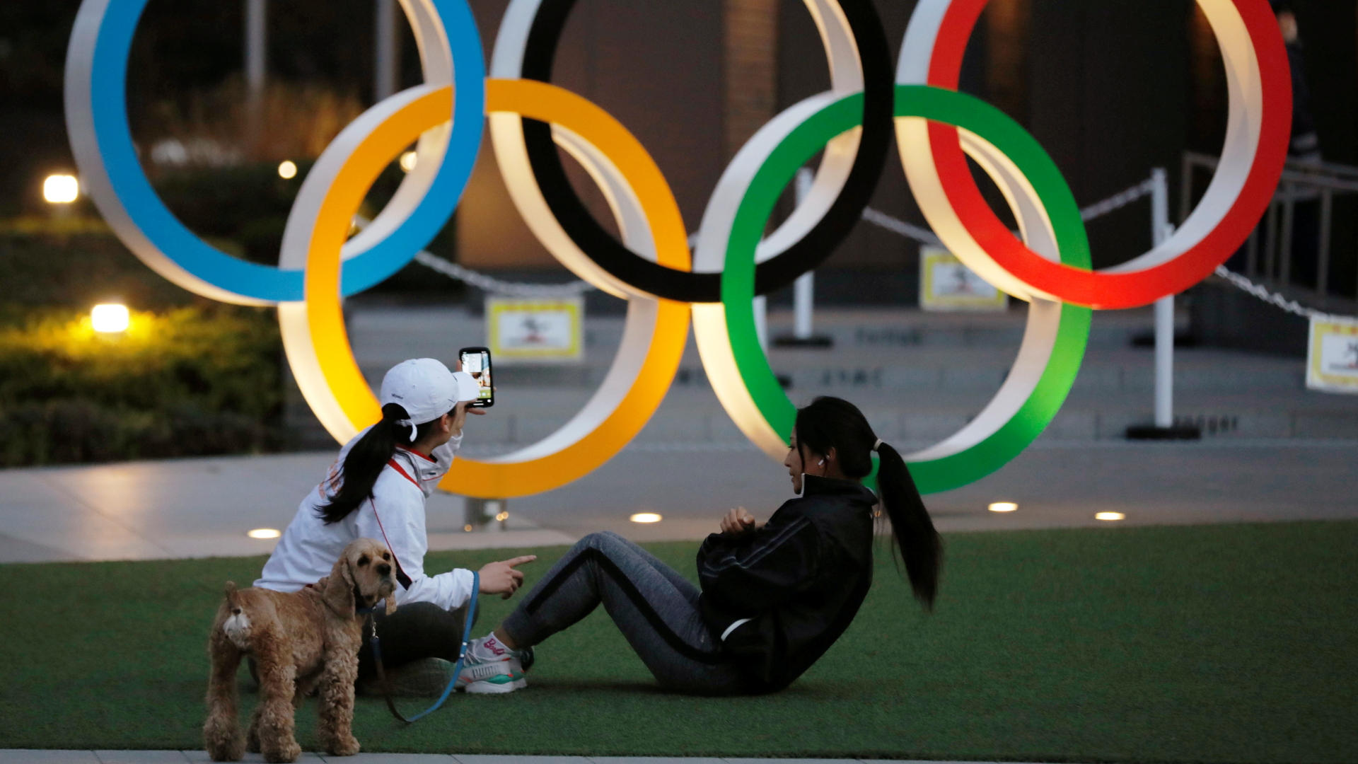 Zwei junge Frauen vor den Olympischen Ringen in Tokio beim Sport.
