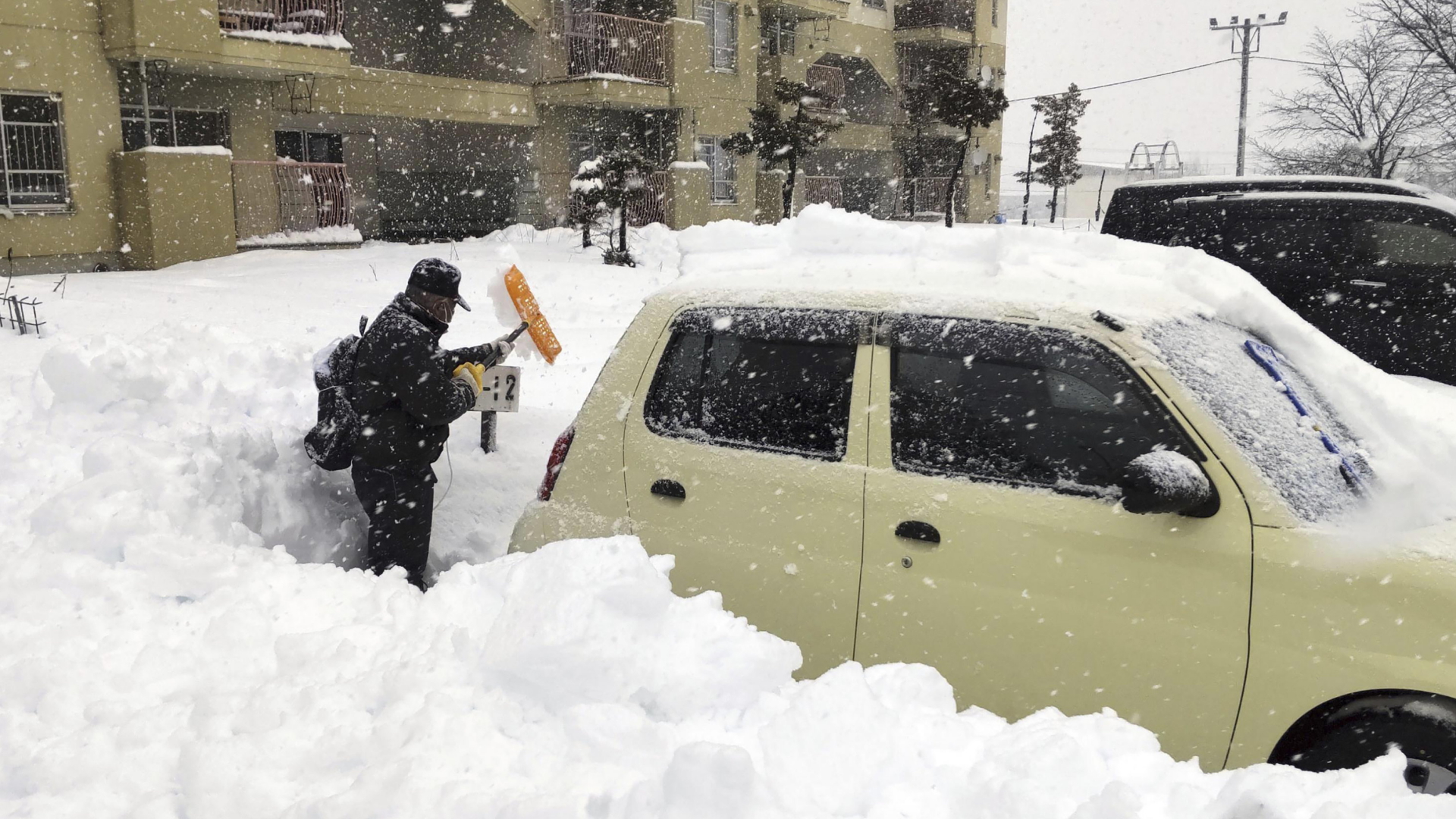 Ein der Präfektur Hokkaido schaufelt ein Mann ein völlig eingeschneites Auto frei. | AP