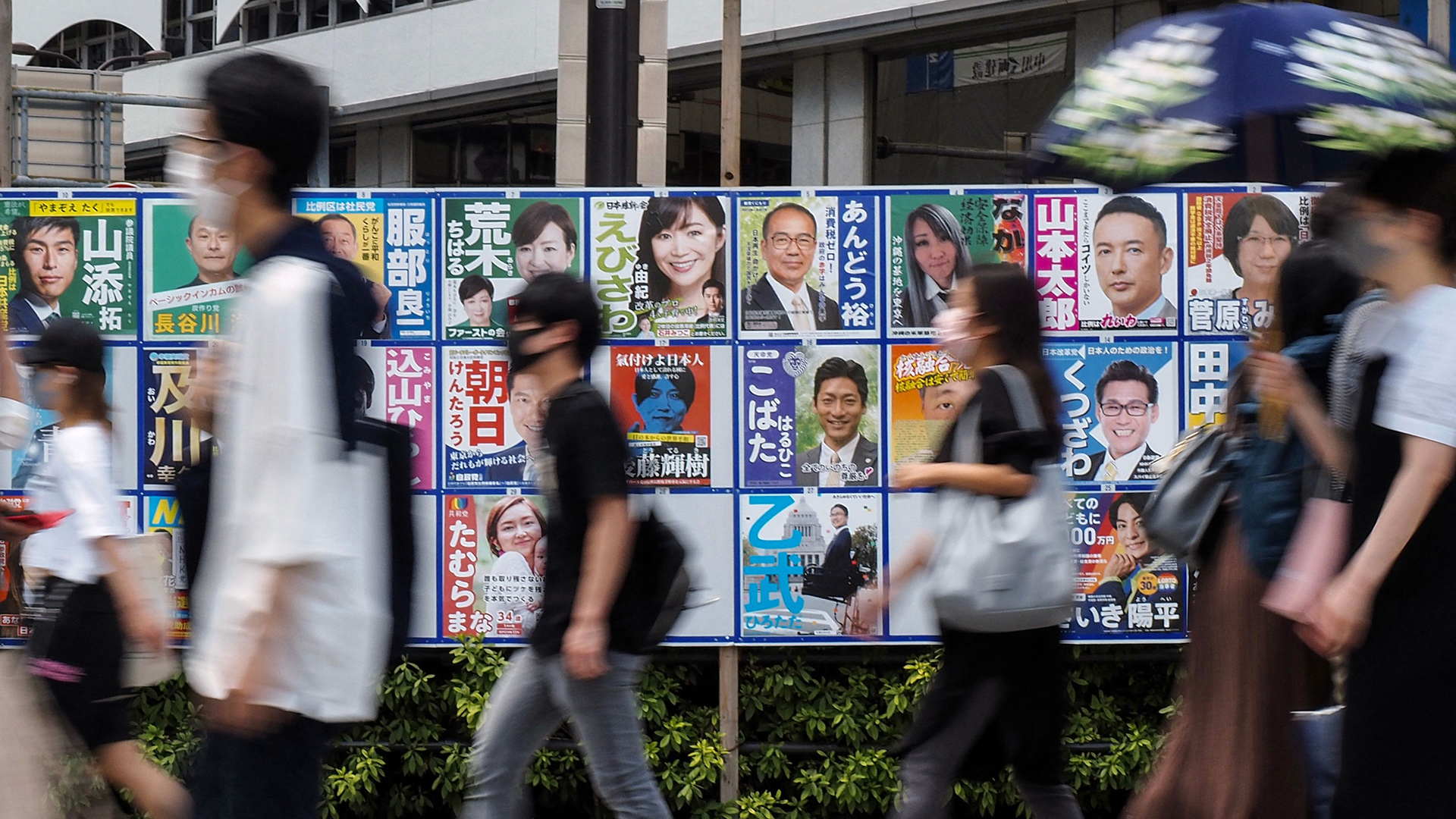 Passanten laufen an Wahlplakaten in Tokio vorbei. | AFP