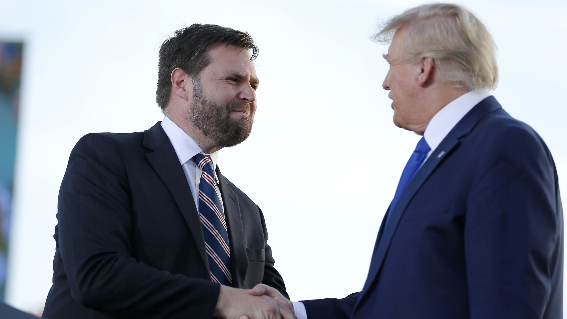 Ex-US-Präsident Donald Trump und JD Vance schütteln einander auf der Wahlkampfbühne die Hände. | AP