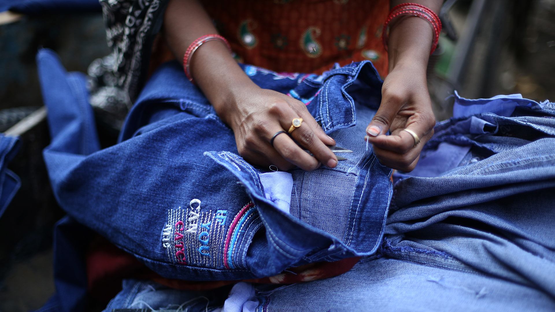Eine Frau näht an einer Jeans. | picture alliance / dpa