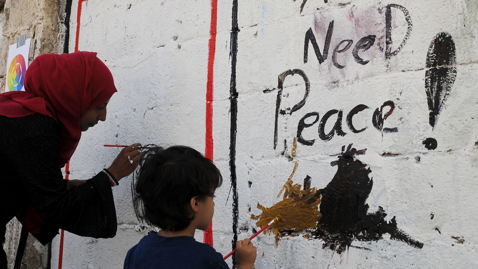 Jemen: Eine Frau und ein Kind malen während einer Kunstaktion Gaffiti an eine Wand | Bildquelle: dpa