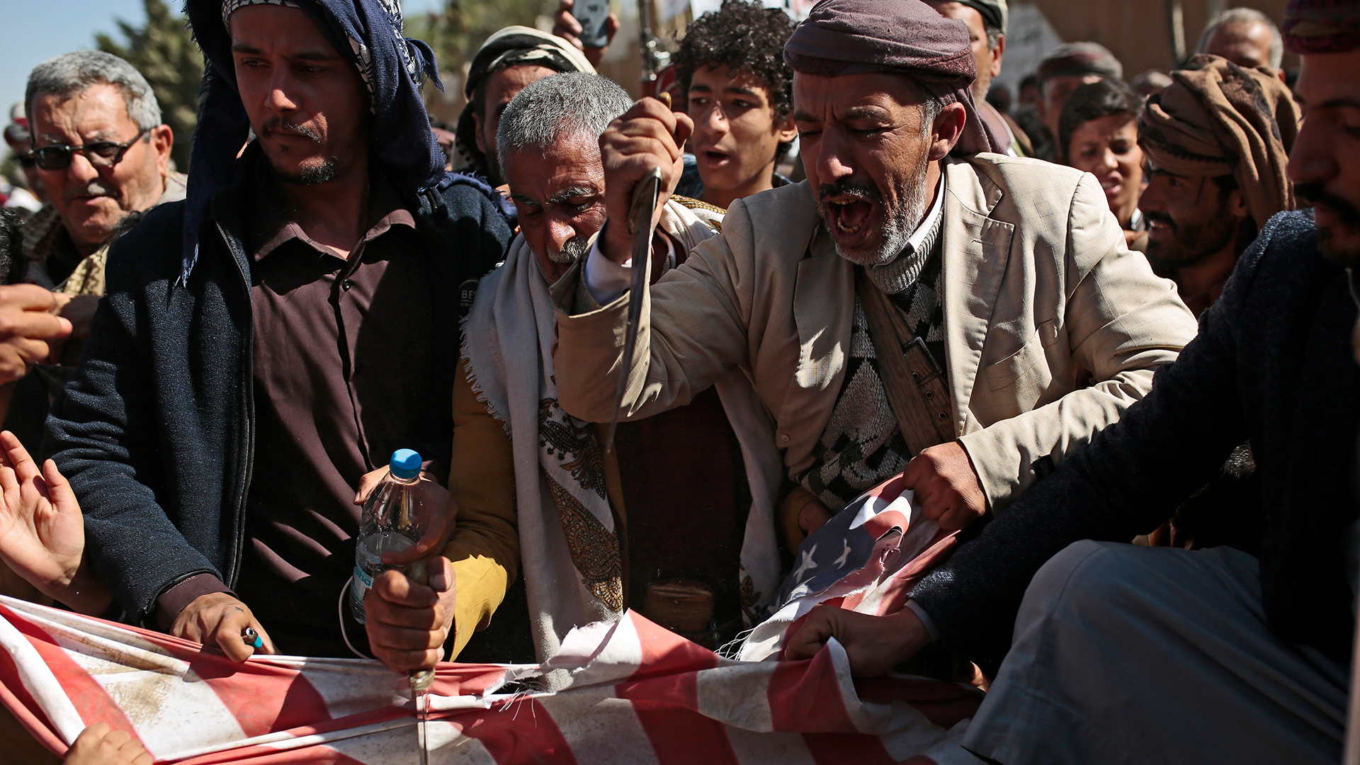 Anhänger der jemenitischen Huthi-Bewegung stechen mit Messern auf eine US-Flagge ein. (Archivbild)| Bildquelle: dpa