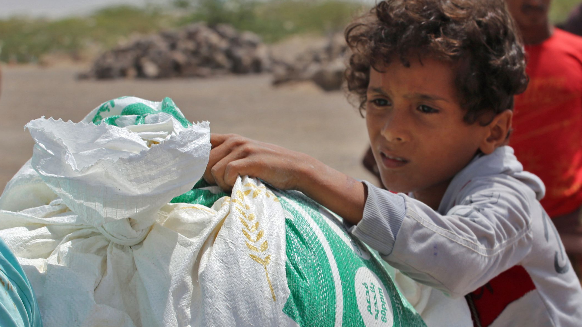 Ein jemenitisches Kind nimmt in einem Flüchtlingslager Grundnahrungsmittel entgegen. | AFP
