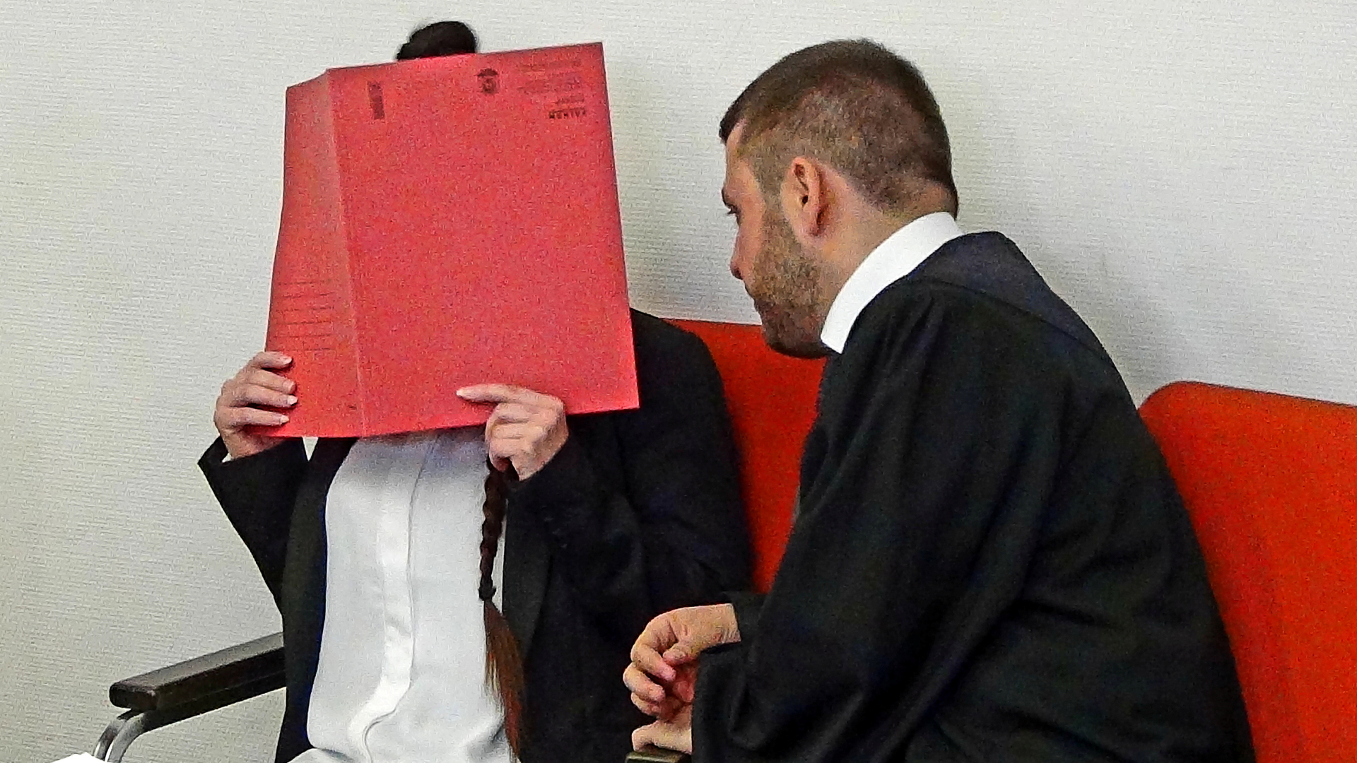 Jennifer W. hält im Münchener Gerichtssaal einen Ordner vor ihr Gesicht. | REUTERS