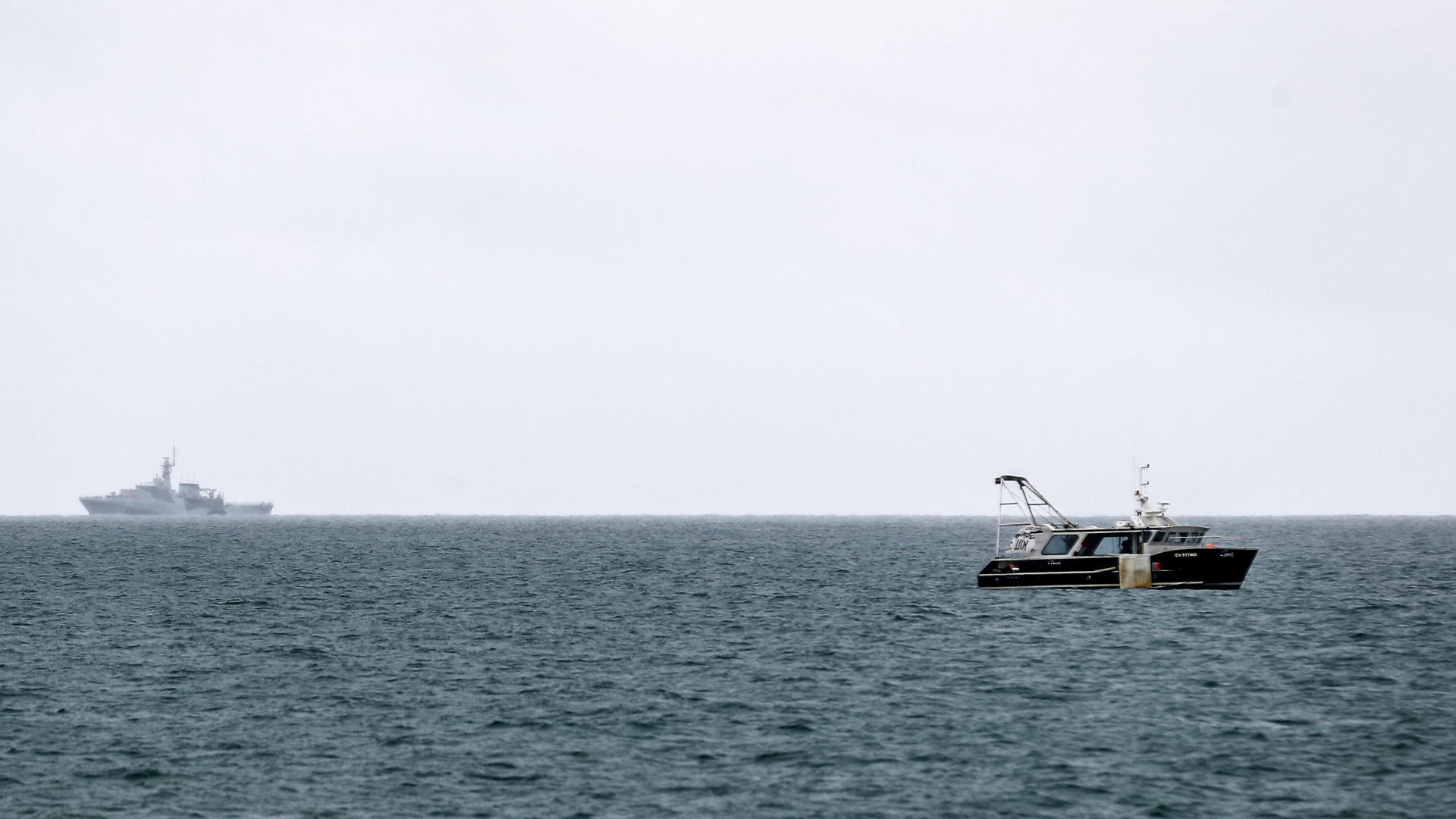 Ein britisches Marineschiff patruilliert hinter einem Fischerboot vor der Küste von Jersey. | AFP