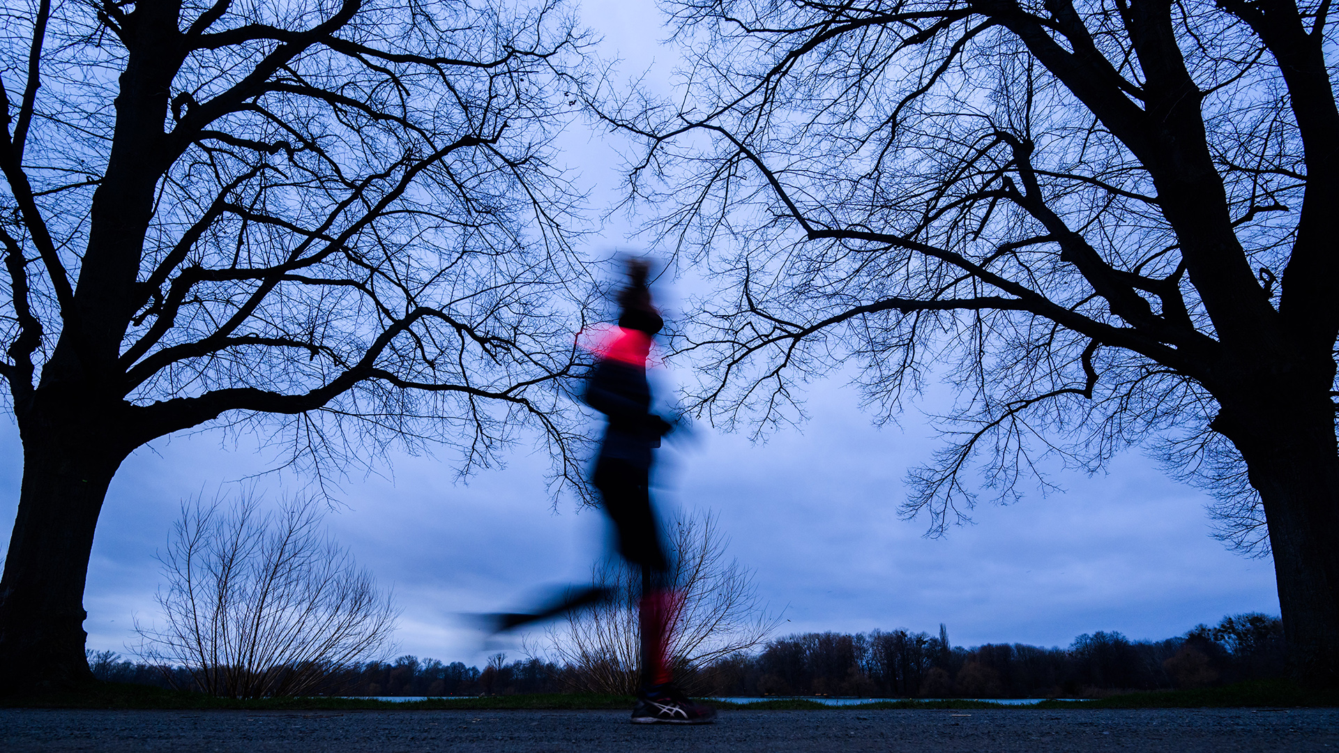Eine Frau joggt in der Morgendämmerung am Maschsee entlang. | picture alliance/dpa