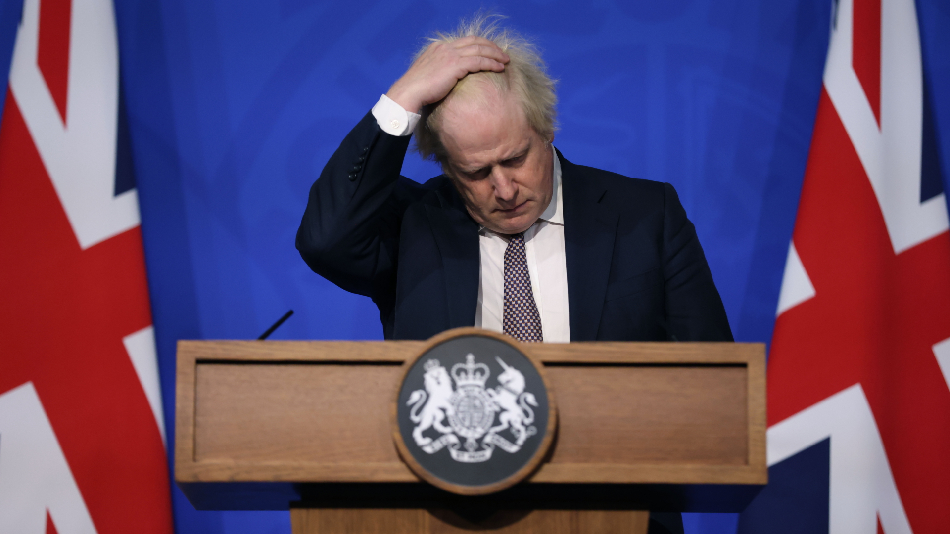 Boris Johnson, Premierminister von Großbritannien, fasst sich mit einer Hand durch die Haare, als er an einer Pressekonferenz zu der neuen Variante des Coronavirus' teilnimmt (Archivbild). | dpa