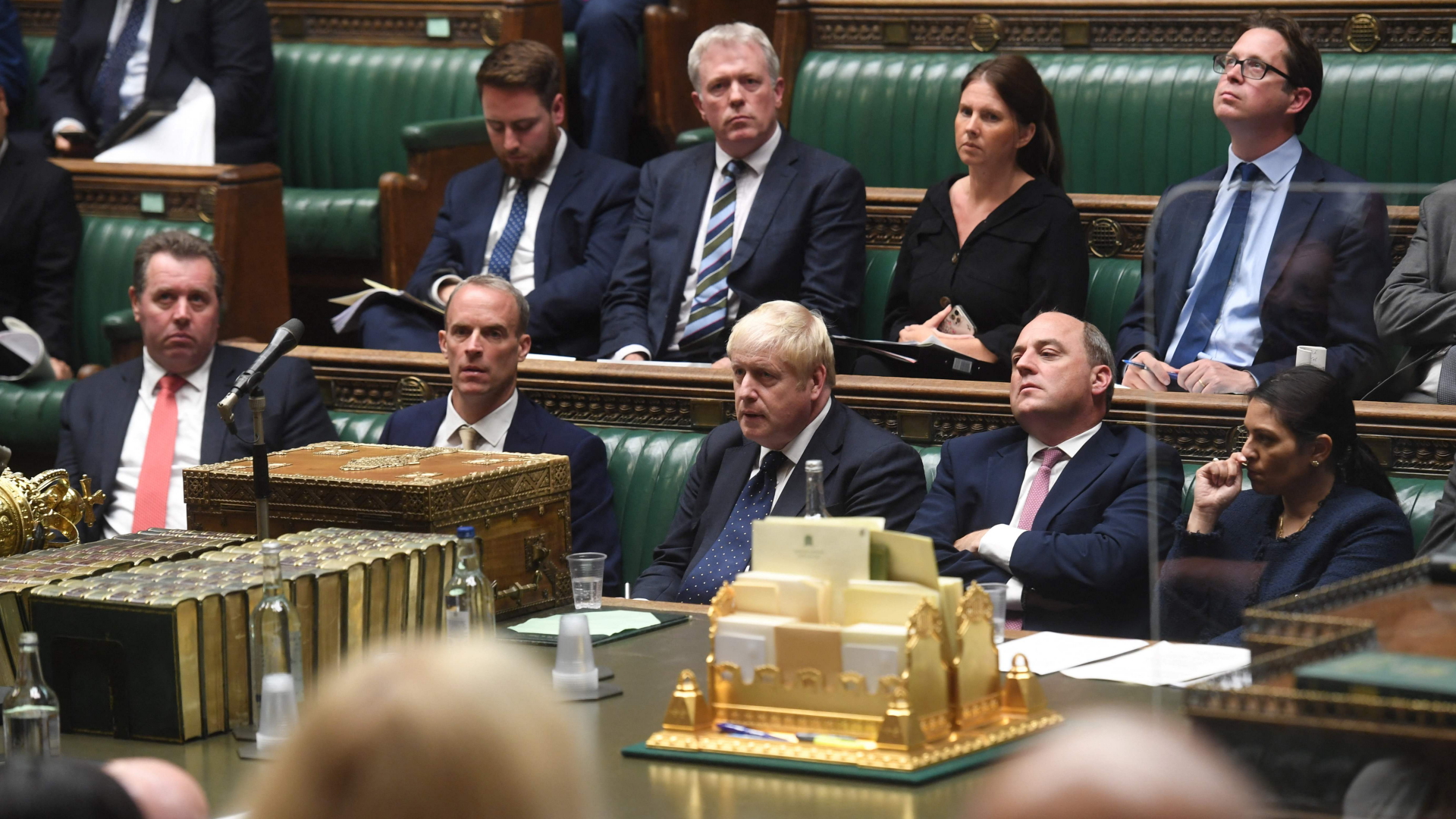 Im britischen Parlament sitzen Außenminister Raab (2.v.l., Premierminister Johnson (3.l.) und Verteidigungsminister Wallace (2.v.r.) während einer Afghanistan-Debatte nebeneinander auf einer Bank | AFP