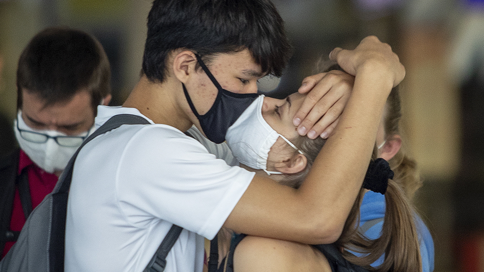 Ein junges Pärchen mit Mund-Nasen-Masken gibt sich einen Abschiedskuss am Frankfurter Flughafen.