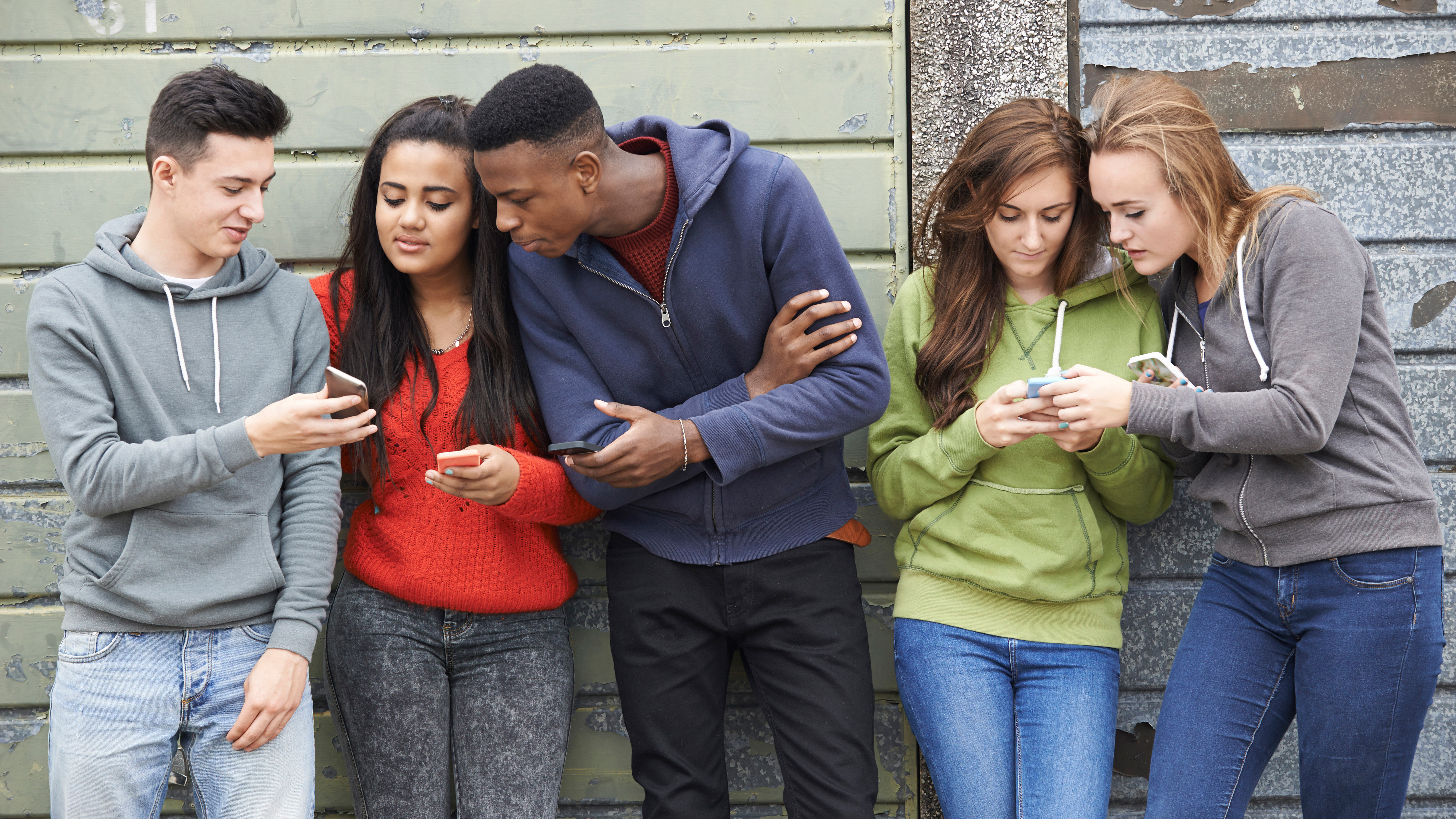 Eine Gruppe Jugendlicher zeigt sich gegenseitig etwas auf dem Smartphone. | picture alliance / Loop Images