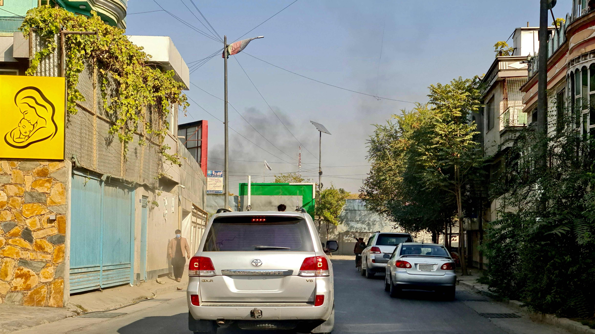 Autos in fahren auf einer Straße in Kabul, im Hintergrund steigt Rauch auf  | AFP