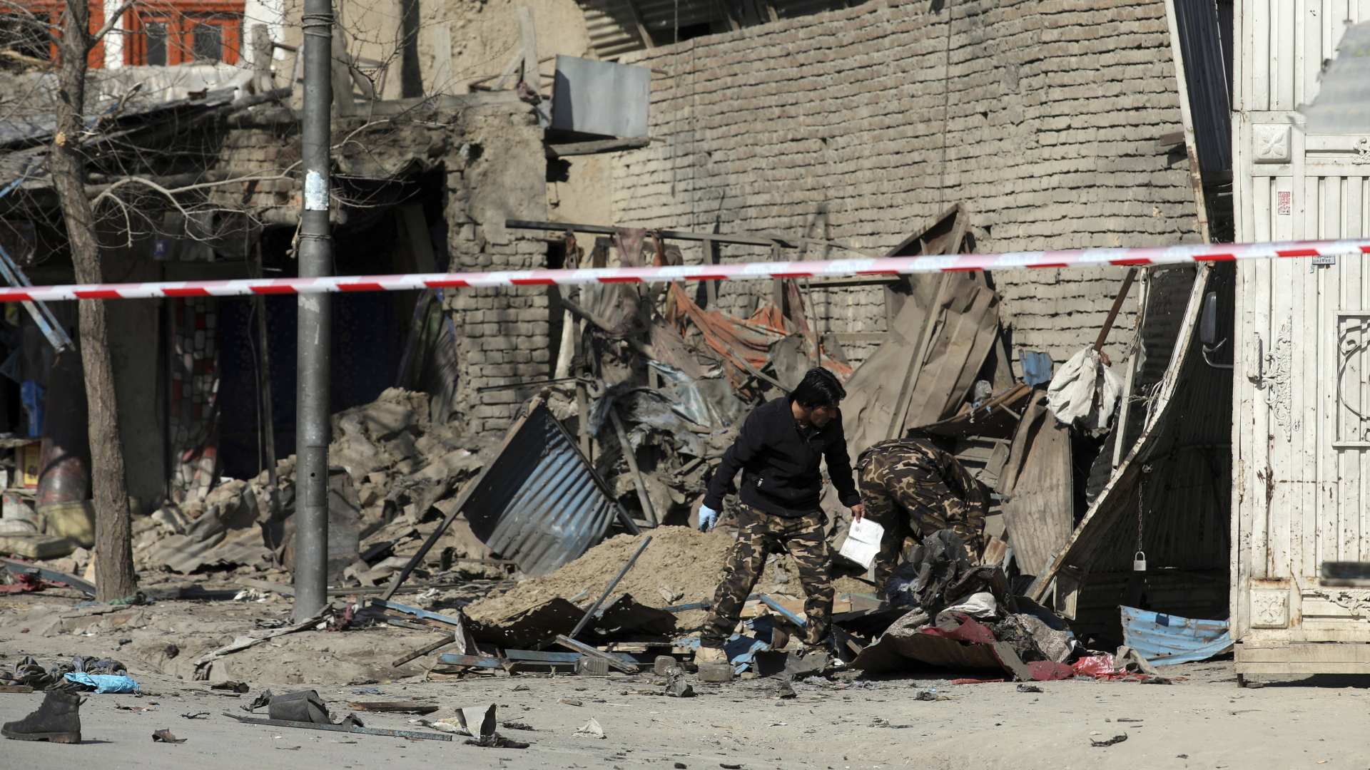 Ein durch einen Bombenanschlag zerstörtes Gebäude in Kabul wird von einem Sicherheitspersonal untersucht. | AP