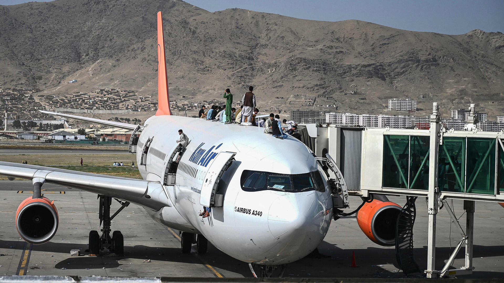 Menschen klettern auf ein Flugzeug am Flughafen in Kabul. | AFP