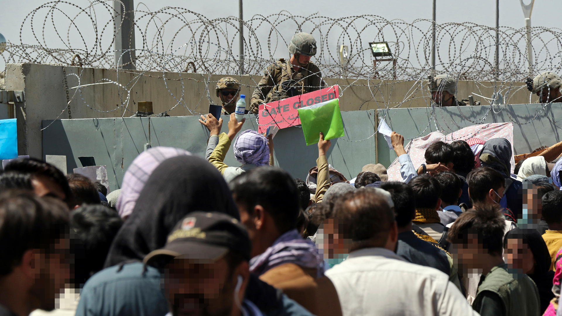 Menschen drängen sich vor einer Mauer am Flughafen in Kabul. | AP