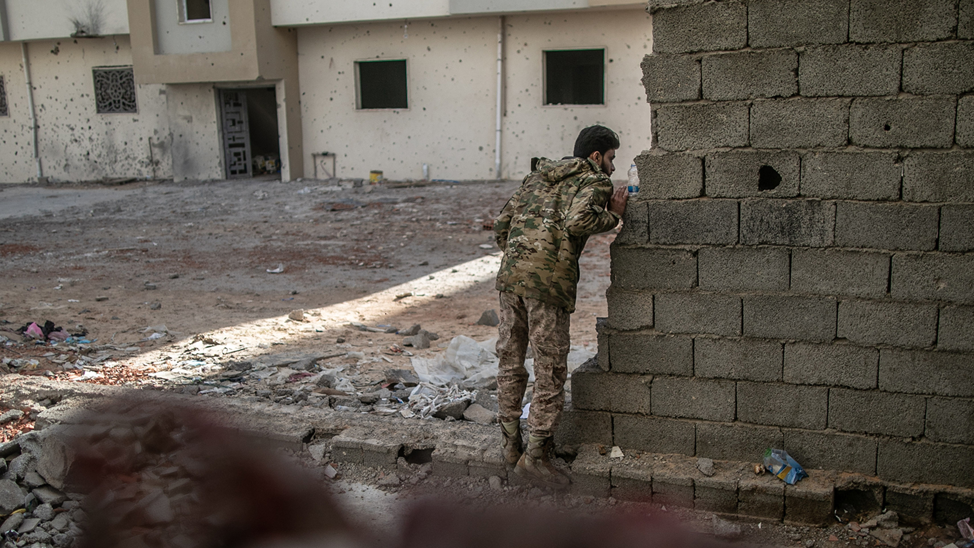 Ein Kämpfer der international anerkannten Regierung schaut während der Zusammenstöße mit den Truppen der Libysch-Nationalen Armee (LNA) um eine Mauer. | dpa