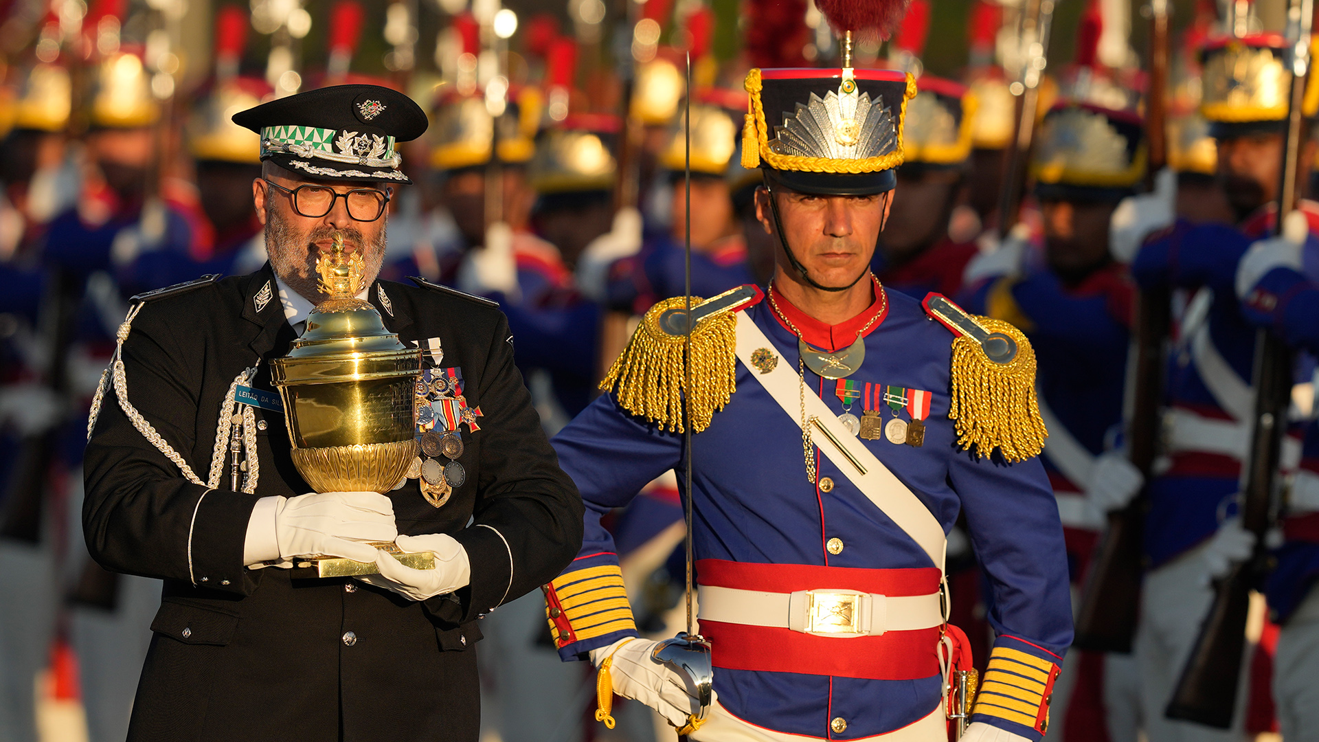 Eine goldene Urne wird auf einer Militärparade präsentiert. | dpa