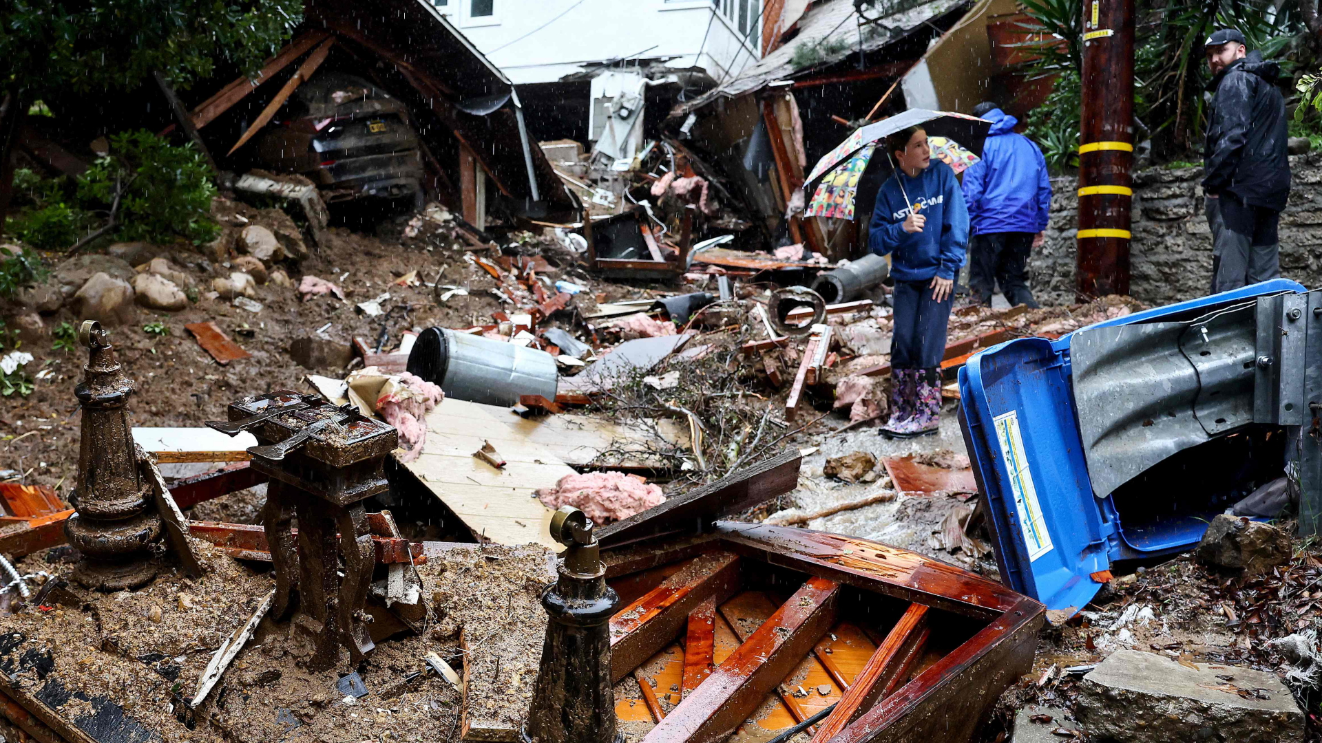 Mehrere Menschen stehen vor einem durch einen Erdrutsch zerstörten Haus in Los Angeles.