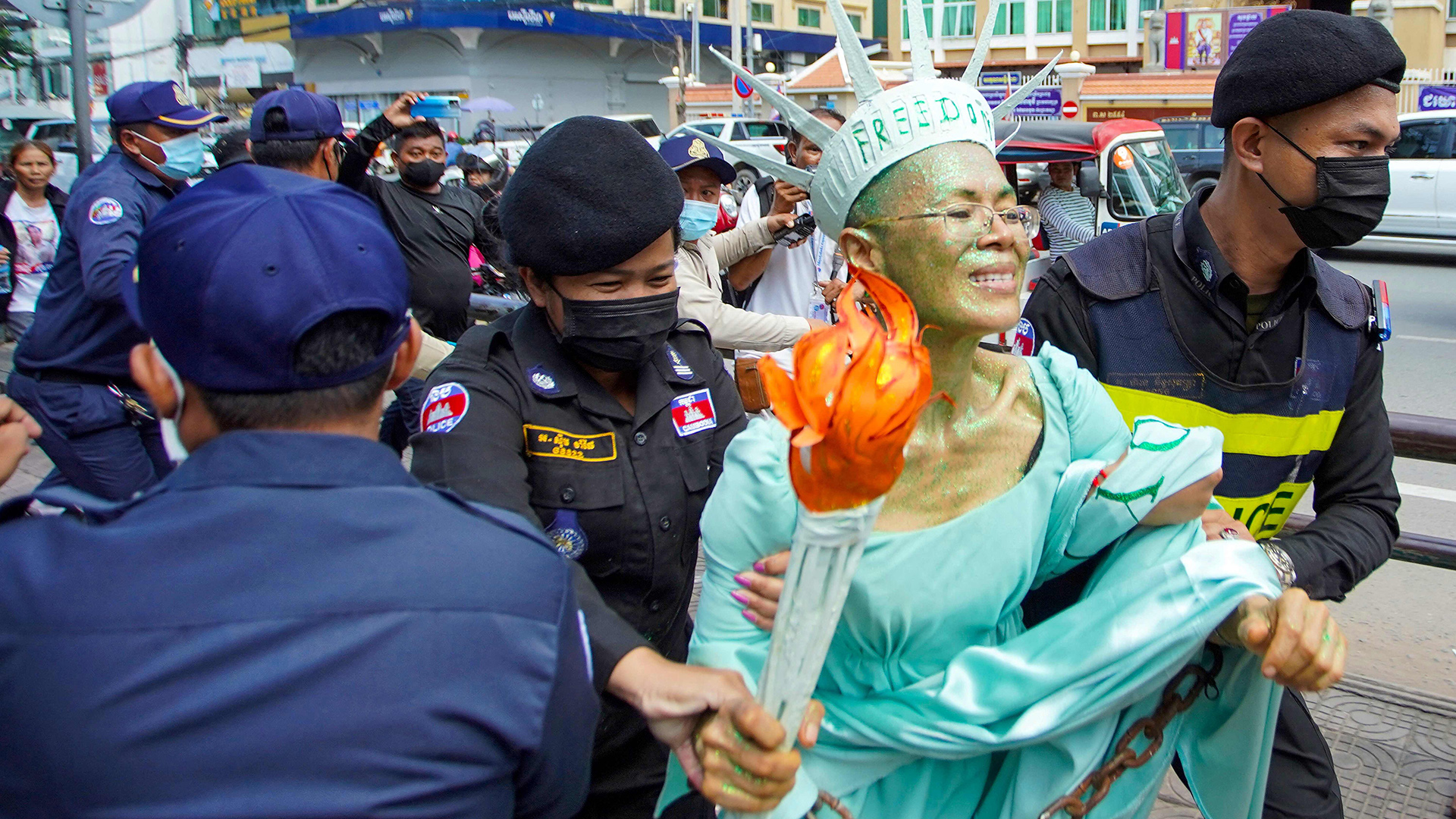 Theary Seng, verkleidet als Freiheitsstatue, wird von Polizisten abgeführt. | AFP