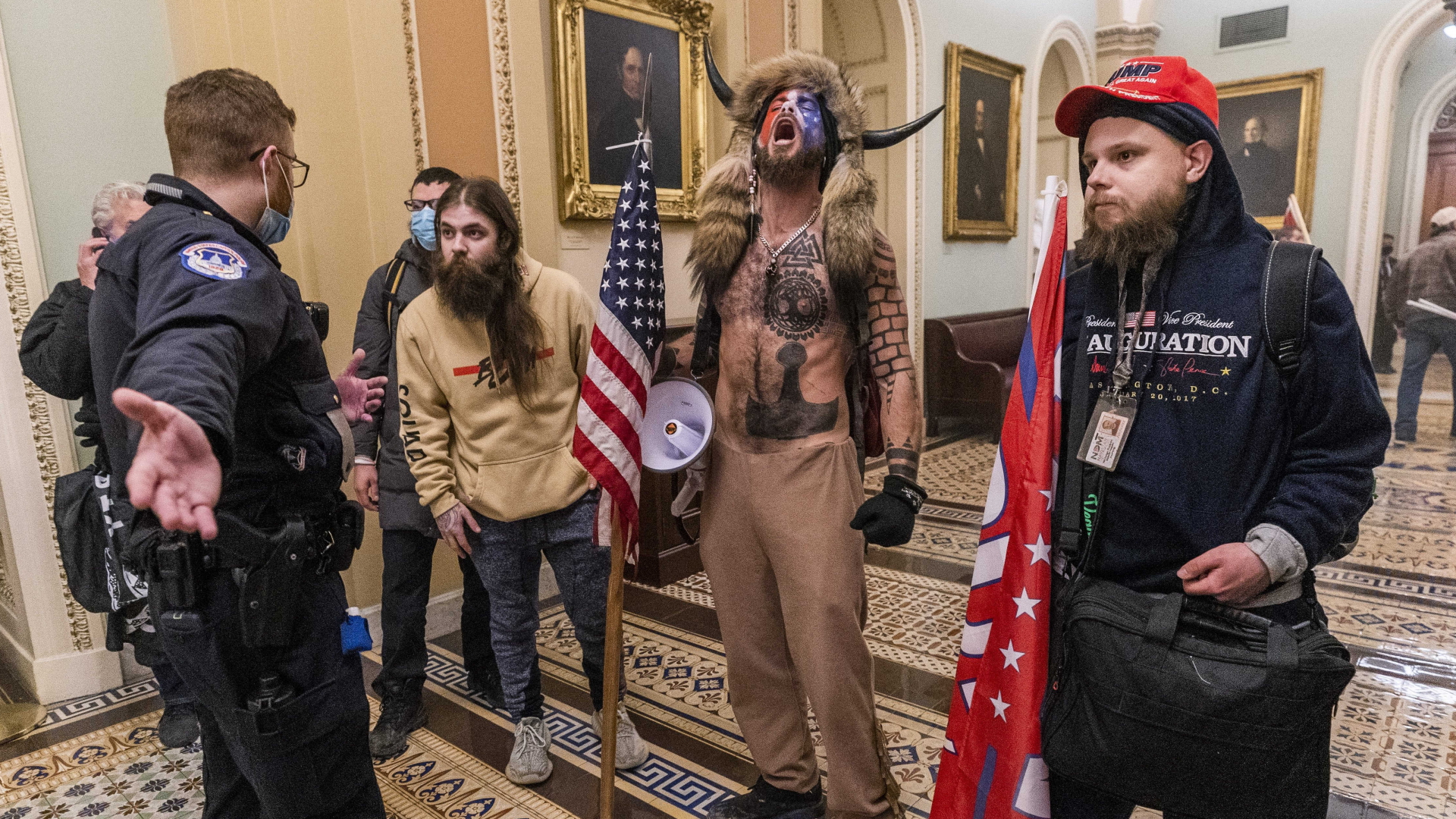 Trump-Unterstützer, darunter der "Schamane" Angeli", stehen am 6.1.2021 im Inneren des Kapitol in Washington (USA) vor einem Polizisten | dpa