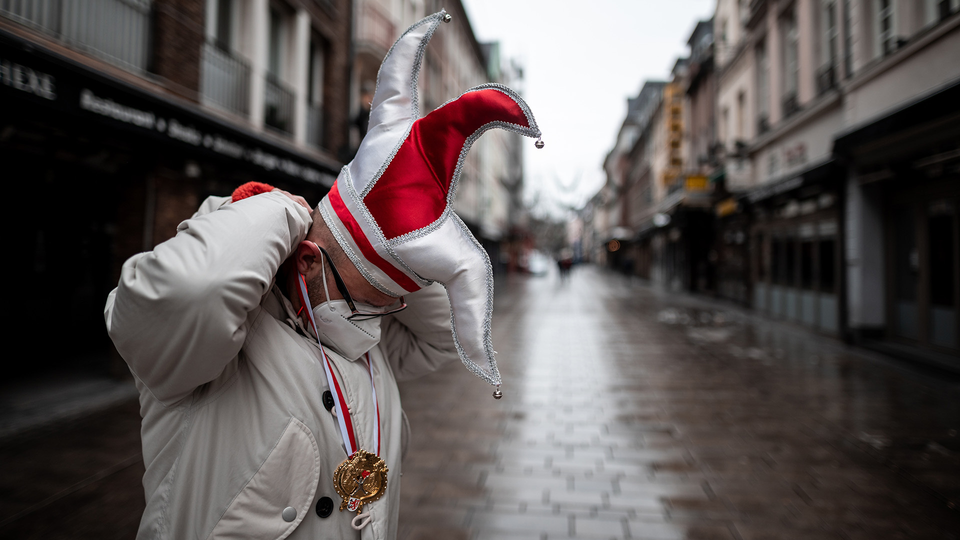 Ein Mann steht mit Karnevals-Mütze in einer Straße in der Düsseldorfer Altstadt. | dpa