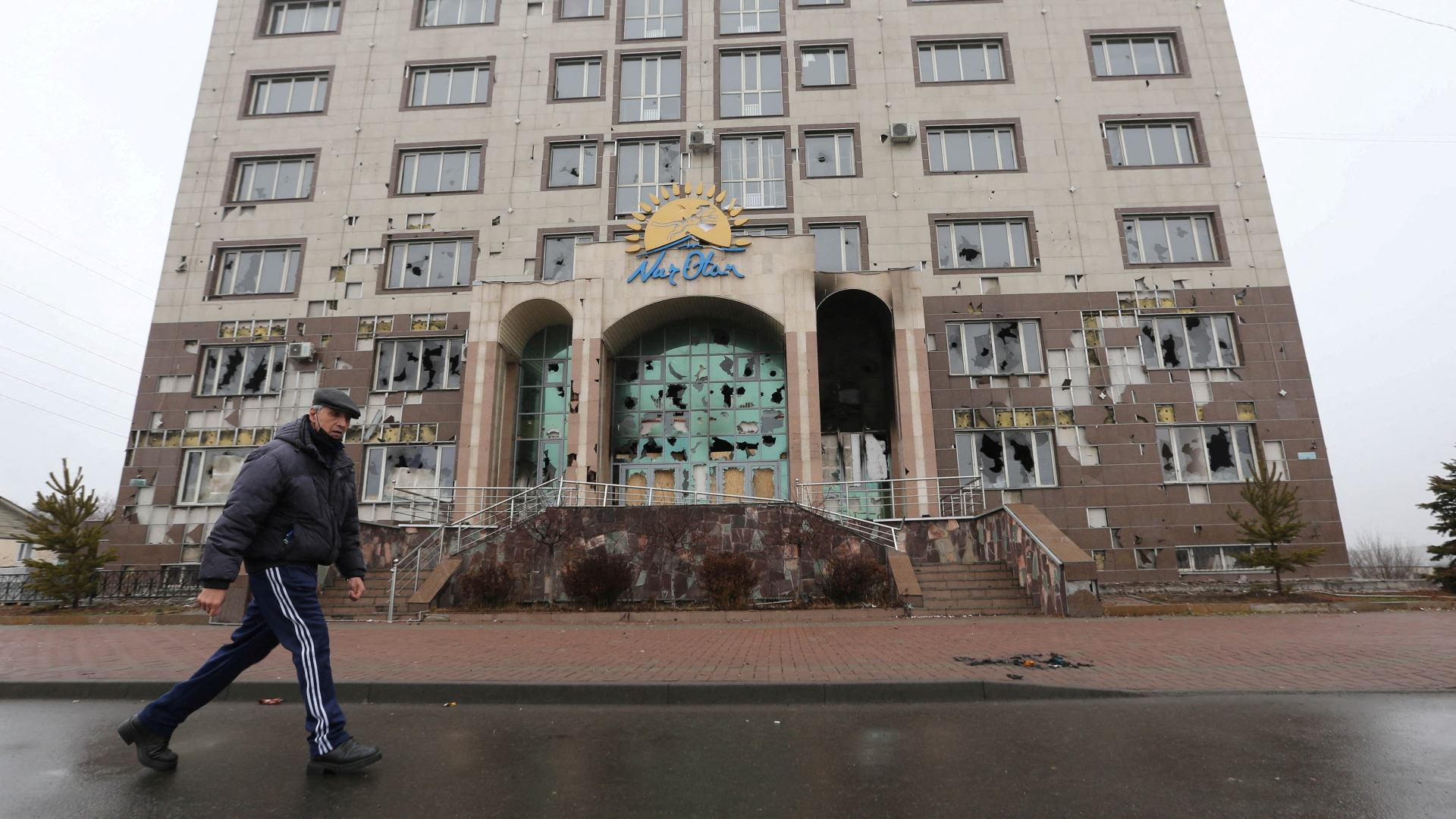 Ein Mann läuft an einem zerstörten Gebäude in Almaty vorbei | REUTERS