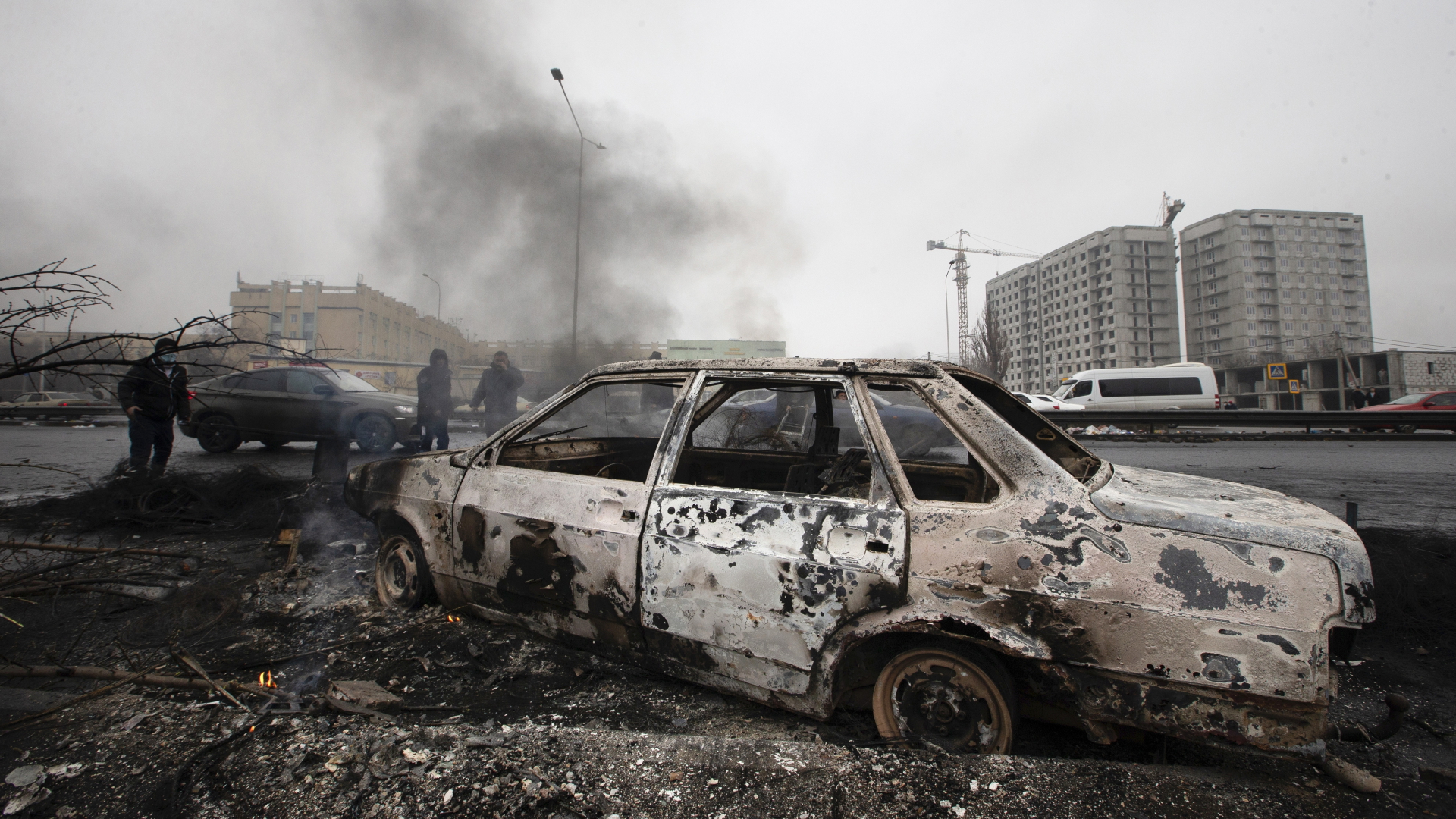Ein Auto, das nach Zusammenstößen in Almaty verbrannt wurde, ist auf einer Straße zu sehen.
