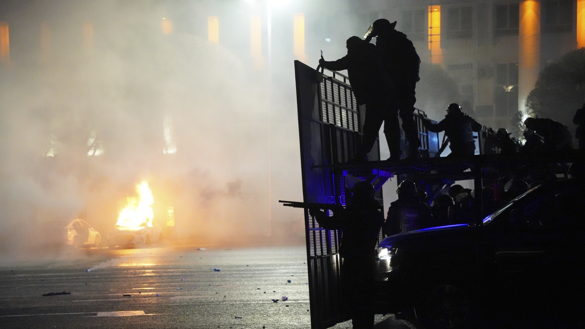 Bereitschaftspolizisten blockieren Demonstranten in der Innenstadt, während im Hintergrund ein Polizeiauto brennt.  | dpa