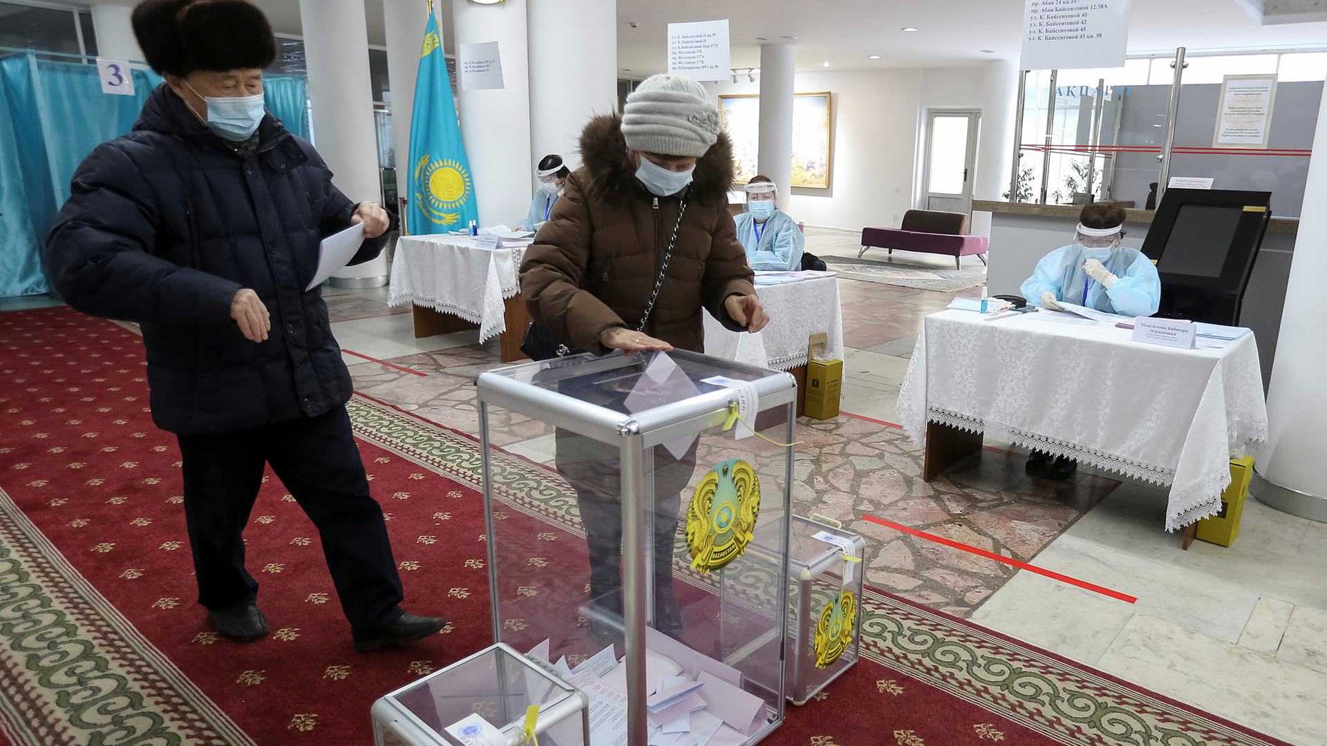 Menschen stecken in einem Wakllokal in Almaty, Kasachstan ihre Stimmzettel in eine Wahlurne. | REUTERS