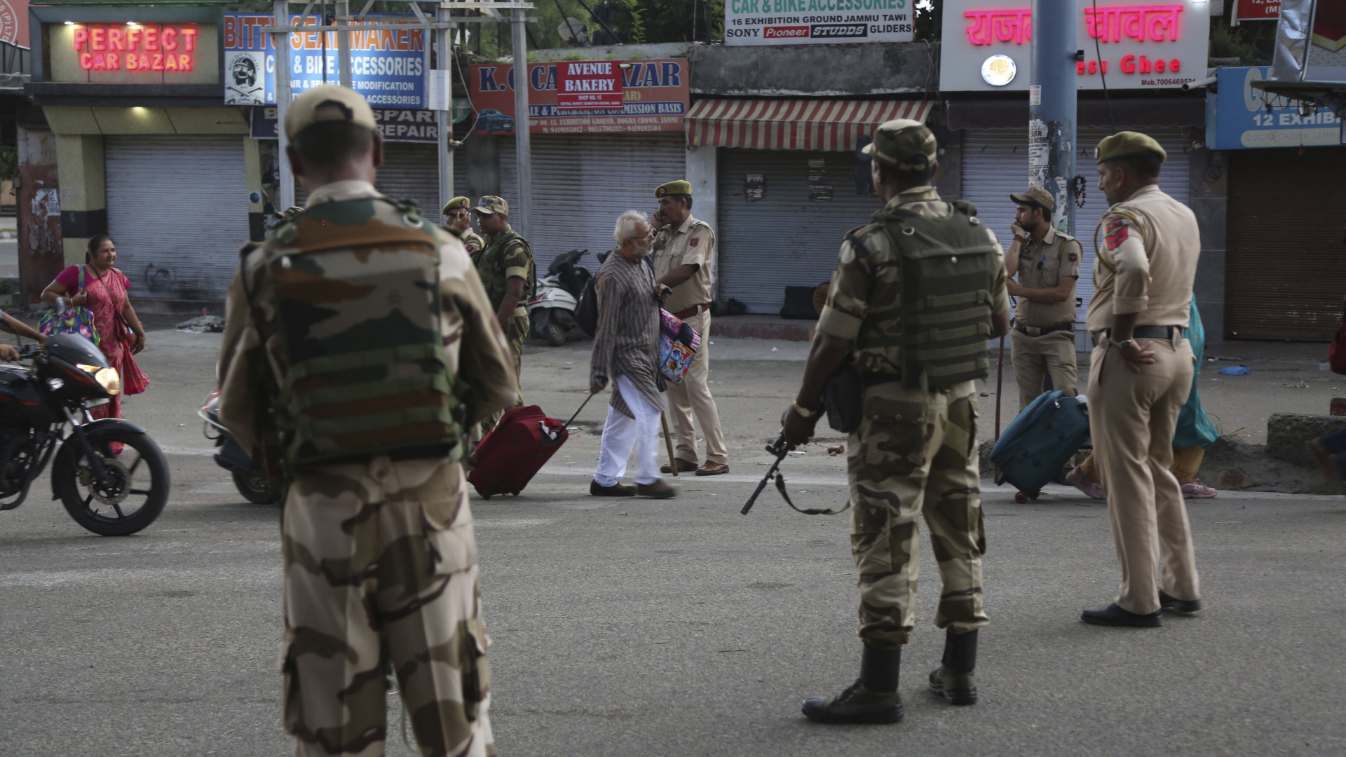 Reisende gehen an bewaffneten Sicherheitskräften in der Stadt Jammu in Kaschmir vorbei. | AP