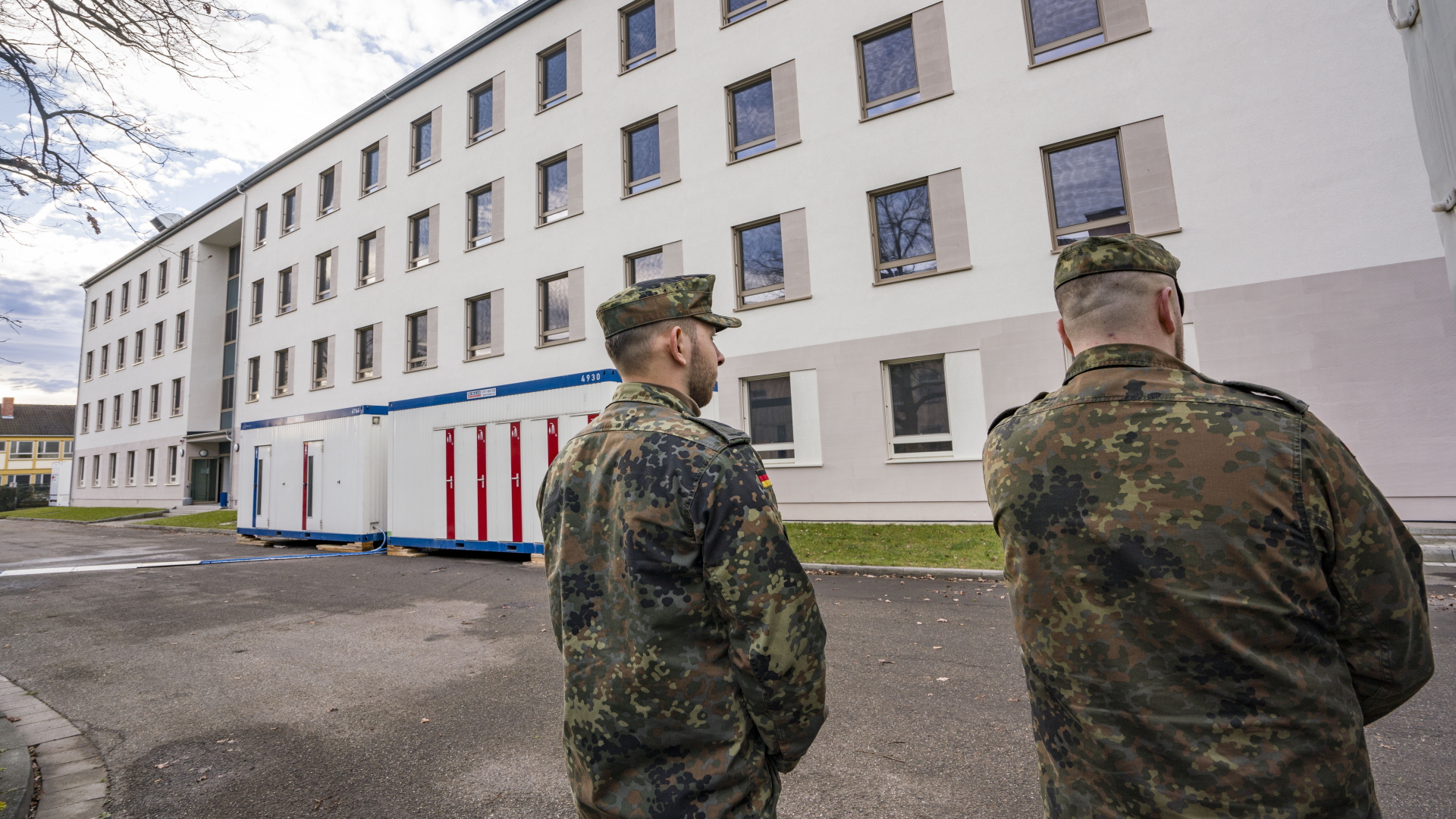 Soldaten stehen auf dem Gelände der Kaserne Südpfalz der Bundeswehr vor dem Gebäude, in dem die Evakuierten wohnen werden. | dpa